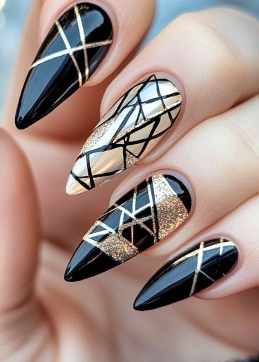 Elegant stiletto nails with geometric designs in black, gold, and nude for a stylish look.