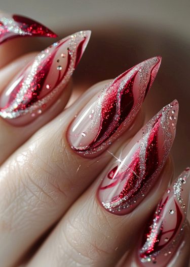 Glamorous red stiletto nails with silver glitter and artistic patterns for a striking look.