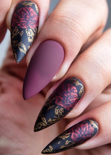 Elegant stiletto nails with intricate floral designs in black, red, and gold.