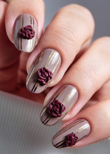 Elegant taupe nail art with gold stripes and burgundy three-dimensional flowers for chic style.