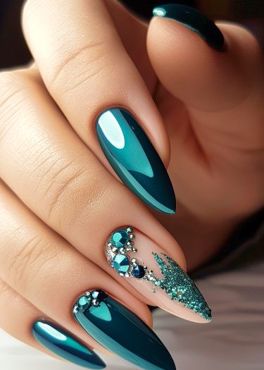 Elegant teal almond-shaped nails with rhinestones and glitter for a luxurious manicure look.