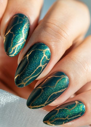 Exquisite emerald green almond nails with gold-veined patterns, showcasing luxurious nail art design.