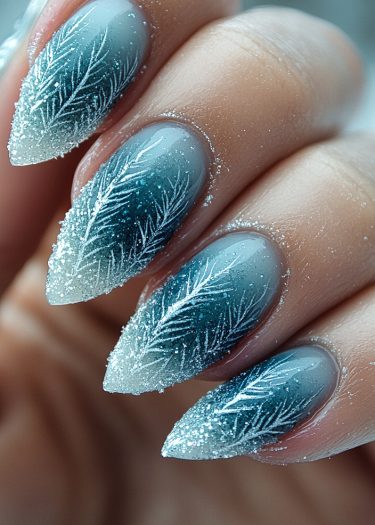 Elegant teal stiletto nails with intricate feather designs and sparkling glitter for stunning nail art.