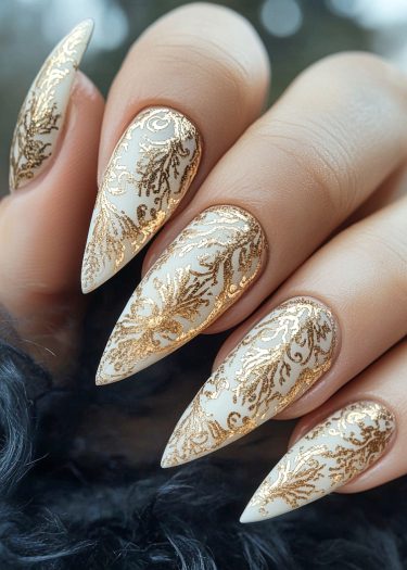 Sophisticated almond-shaped nails featuring intricate metallic gold floral designs on a creamy base.