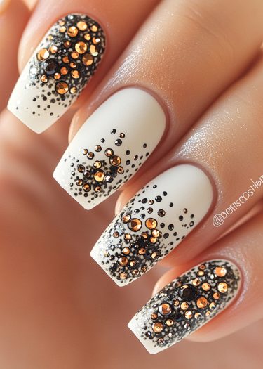 Elegant white nail art with glamorous gold and silver gems for a sophisticated look.