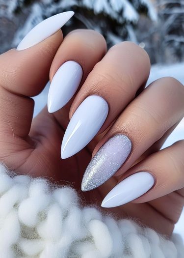 Elegant white almond-shaped nails with glitter accent in a cozy winter setting.