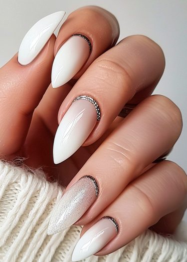 Elegant white stiletto nails with glitter, rhinestones, and a textured background.