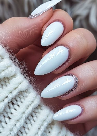 Elegant white stiletto nails with rhinestones on a cozy knitted background.