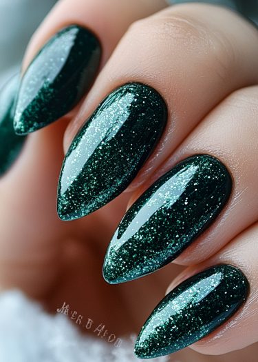 Stunning emerald green stiletto nails with glitter, showcasing elegant nail artistry and manicure care.