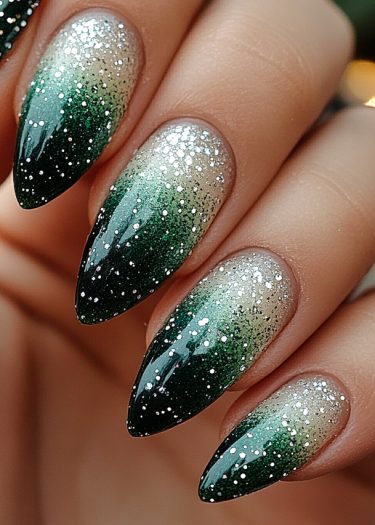 Elegant emerald glitter stiletto nails with seamless gradient design and professional manicure.