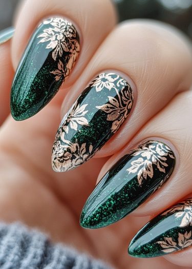 Elegant emerald green nails with gold floral designs, showcasing sophisticated nail art.