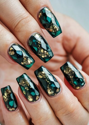 Luxurious emerald green nail art with gold foil accents for an elegant look.