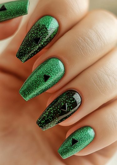 Stunning emerald green stiletto nails featuring intricate speckles and bold triangular accents.