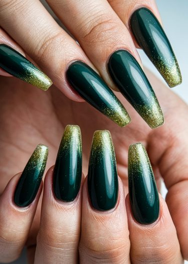 Elegant emerald green nails with gold gradient and glitter for sophisticated nail art.