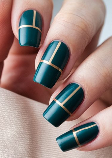 Elegant dark teal nail art with gold geometric design on a manicured hand.