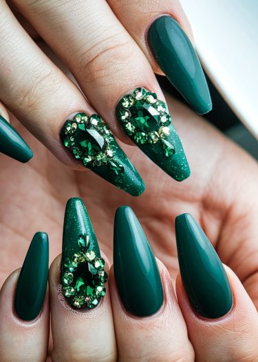 Elegant emerald green stiletto nails with sparkling rhinestones for a luxurious nail art design.