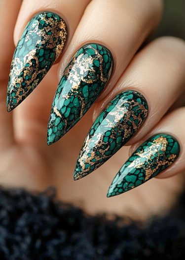 Emerald green stiletto nails with gold filigree pattern showcase luxurious nail art design.