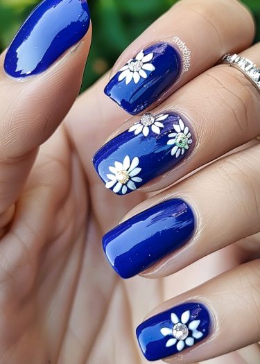 Gorgeous blue nail art featuring floral designs and rhinestones, perfect for a chic manicure.