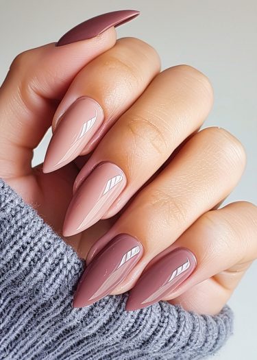 Elegant mauve almond nails with chic designs, complemented by a cozy gray sweater.