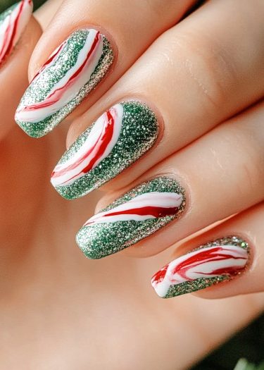 Festive green glitter nails with vibrant red and white swirls for a glam holiday look.