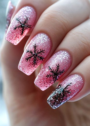 Elegant pink glitter nails with black snowflake designs for a festive winter look.