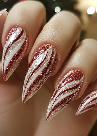 Stiletto nails featuring red, white, and silver glitter in a festive candy cane design.