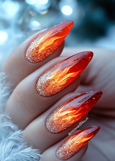 Stunning flame-inspired nail art with glossy orange-red tips and sparkling glitter ombre.