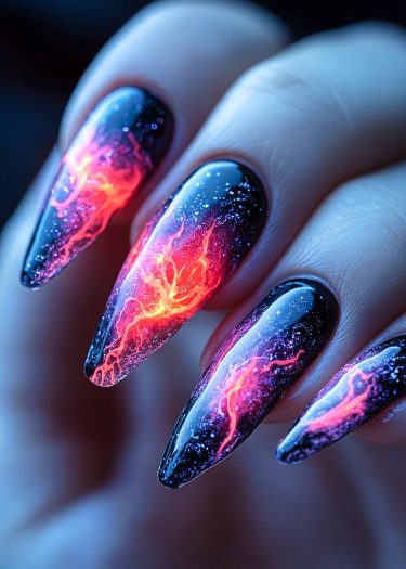 Vibrant fiery stiletto nail art on glossy black nails with glowing patterns.