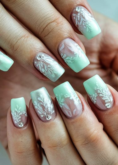 Elegant mint green floral gradient nail art with intricate designs and sparkling rhinestones.