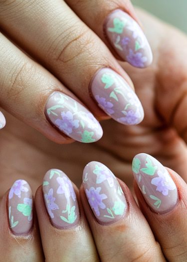 Almond-shaped floral nail art with pastel flowers on a nude base, perfect for spring.