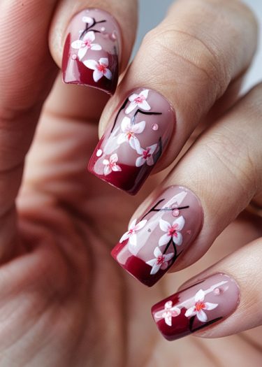 Elegant floral nail art with maroon ombre and intricate designs for a sophisticated look.