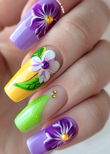 Vibrant floral nail art design with purple and yellow blooms, jewels, and intricate details.