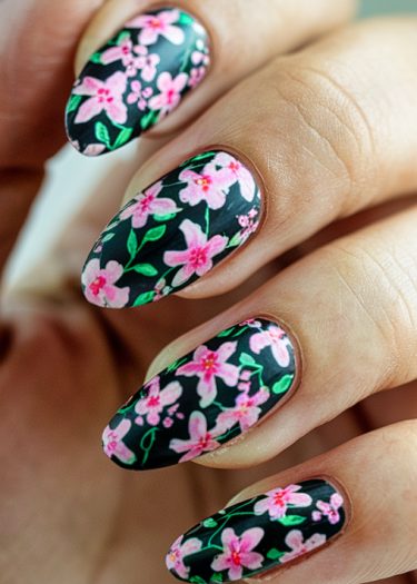 Intricate floral nail art with pink flowers and elegant almond shapes on a polished background.