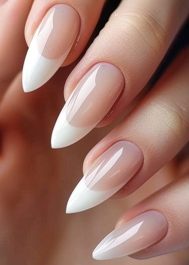 Elegant stiletto nails with glossy French tips showcase refined beauty and meticulous nail art.