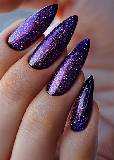 Glamorous galaxy nail art with a starry night design in deep purples, blues, and glitter.