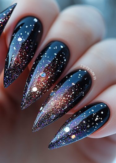 Stunning galaxy stiletto nails with black base, holographic glitter, and cosmic gradient design.