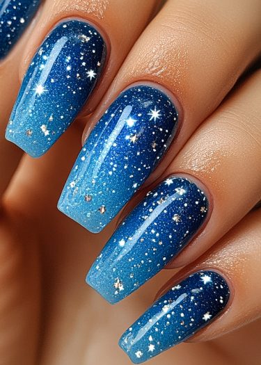 Elegant galaxy nail art featuring a stunning blue gradient and starry designs.