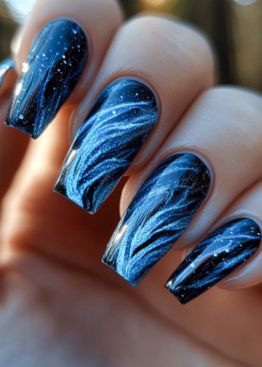 Elegant galaxy nail art featuring long, square-shaped nails with shimmering blue designs.