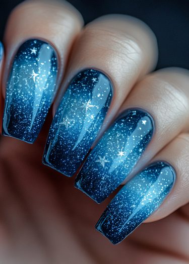 Elegant galaxy nail art with a stunning blue gradient and shimmering star designs.