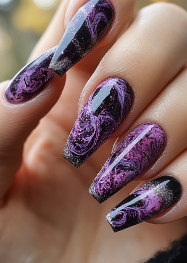 Elegant galaxy-inspired purple and black nail art with marbled design and sparkling glitter.