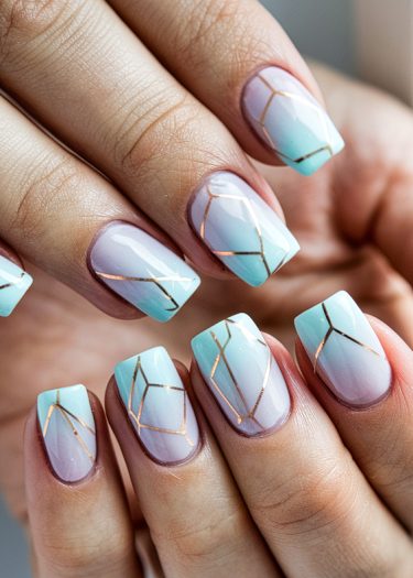 Stylish geometric gradient nails in lavender and turquoise with metallic gold accents.