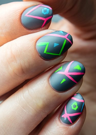 Intricate geometric nail art on matte gray base, featuring vibrant pink, blue, and green designs.