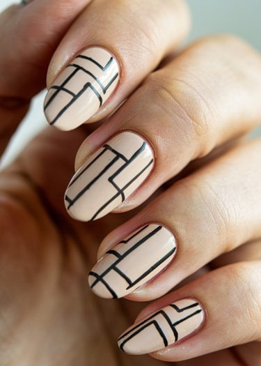 Elegant almond-shaped nails featuring nude polish and striking geometric black line art.