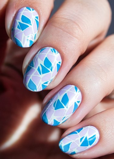 Intricate geometric nail art in blue and purple with a glossy stained glass design.