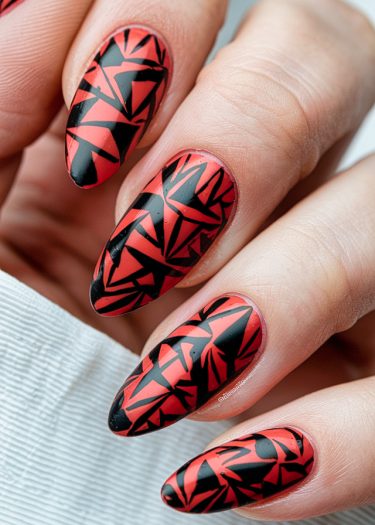 Bold red and black almond-shaped nail art featuring geometric designs for a modern look.