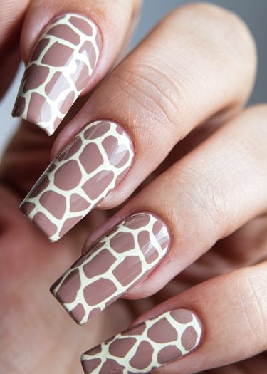 Elegant giraffe print nail art on manicured nails, showcasing a stylish and sophisticated design.