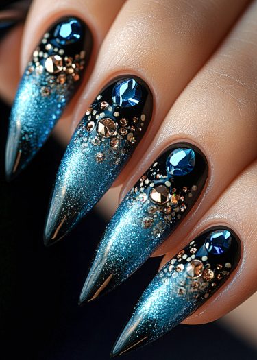 Glamorous stiletto nails featuring a blue gradient with sparkling gemstones and metallic accents.