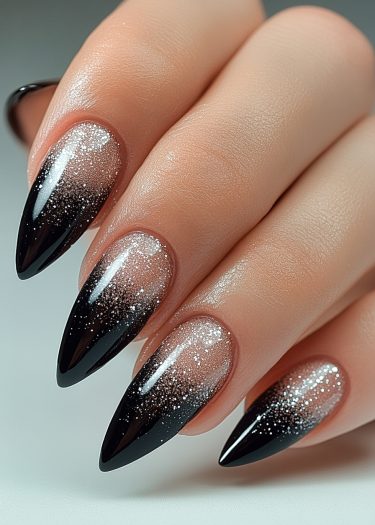 Elegant black and silver glitter gradient nail art on almond-shaped nails.