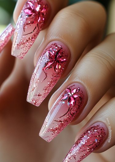 Elegant pink coffin nails with glitter and three-dimensional floral nail art design.