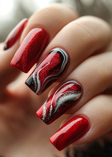 Elegant glittery red nails with artistic black design and silver accents showcase stunning nail art.